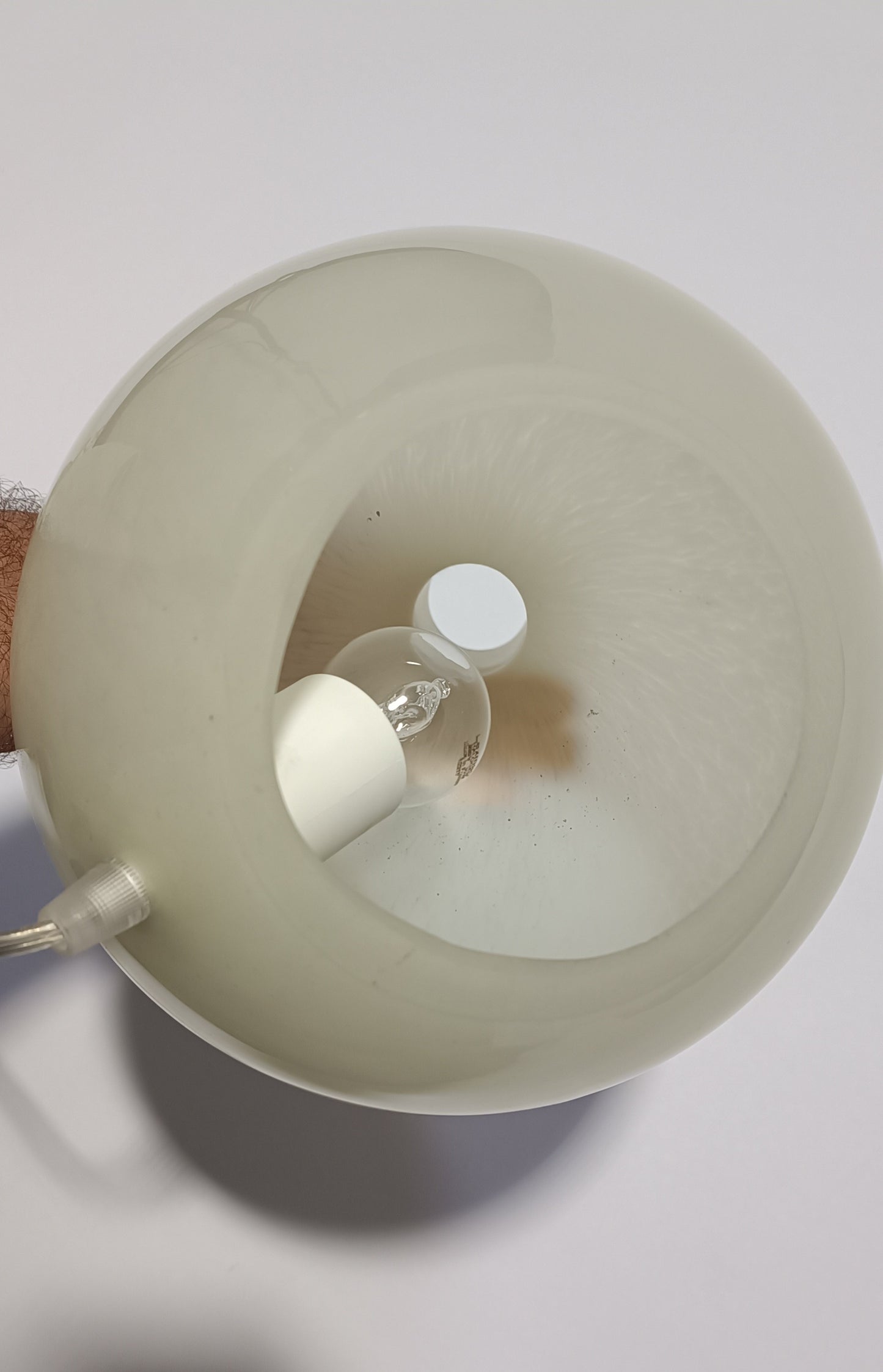 Vista superior do candeeiro Halo Brando aceso, com brilho suave visível na superfície.